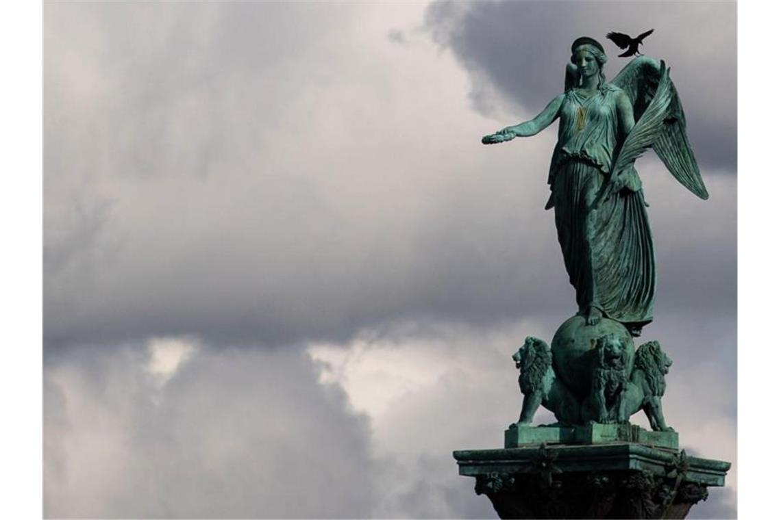 Viele Wolken und sinkende Temperaturen im Südwesten erwartet Eine Krähe sitzt auf einer Statue der römischen Göttin Concordia, die auf der Jubiläumssäule auf dem Schlossplatz thront. Foto: Marijan Murat/dpa