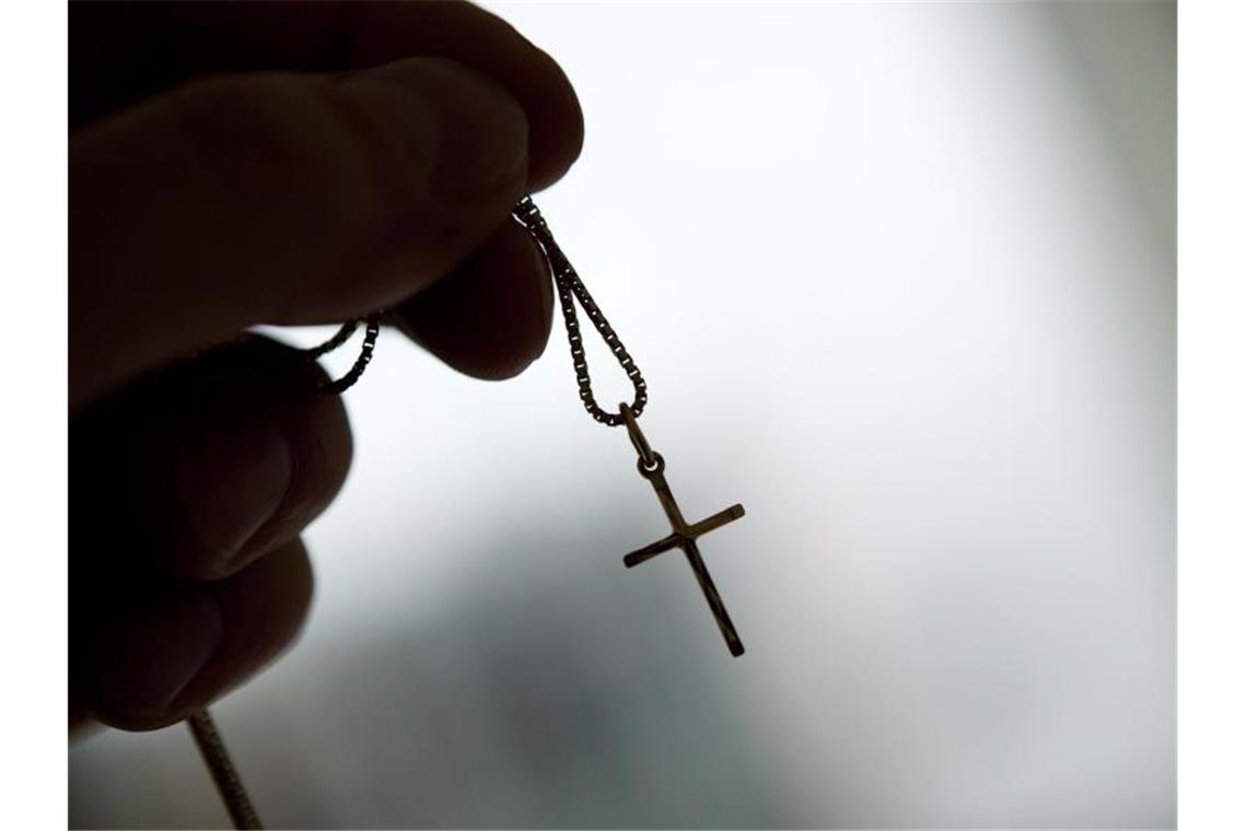 Eine Kreuzkette wird in einer Hand gehalten. Foto: Andrea Warnecke/dpa-tmn/Symbolbild