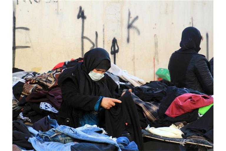 Eine Kundin schaut sich gebrauchte Kleidungsstücke auf einem zentralen Markt in Tunesiens Hauptstadt an. Foto: Cindy Riechau/dpa