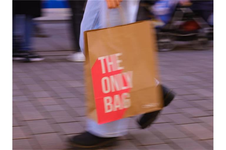 Eine Kundin trägt eine Einkaufstüte durch die Innenstadt. Dass weniger Konsum der Umwelt und dem Klima nutzt, ist fast allen Menschen klar. Und doch kaufen viele gern und viel mehr, als sie wirklich brauchen. Foto: Ulrich Perrey/dpa