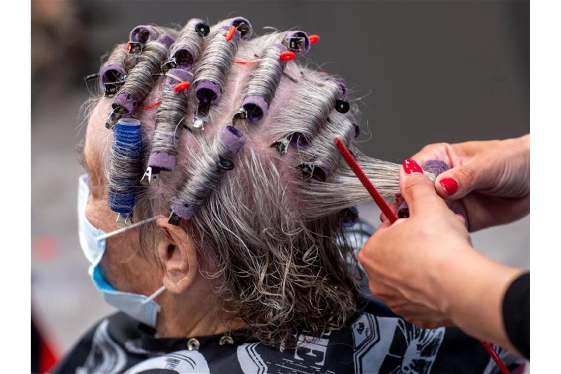 Friseure senden finanziellen „Notruf“ aus dem Lockdown Eine Kundin trägt im Frühjahr 2020 Mundschutz in einem Friseursalon. Vielen Betrieben droht im anhaltenden Corona-Lockdown das Aus. Foto: Jens Büttner/dpa-Zentralbild/dpa