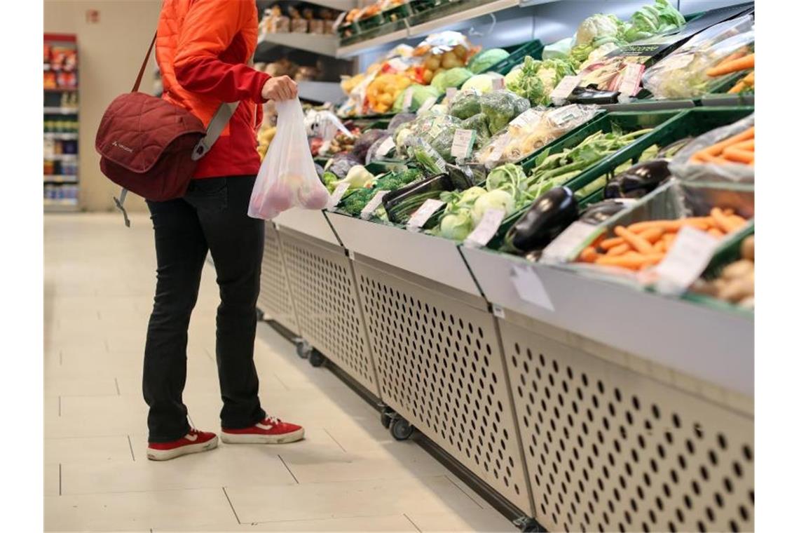 Eine Kundin wählt ihre Einkäufe in der Obst- und Gemüseabteilung eines Supermarktes aus. Foto: Jan Woitas/zb/dpa