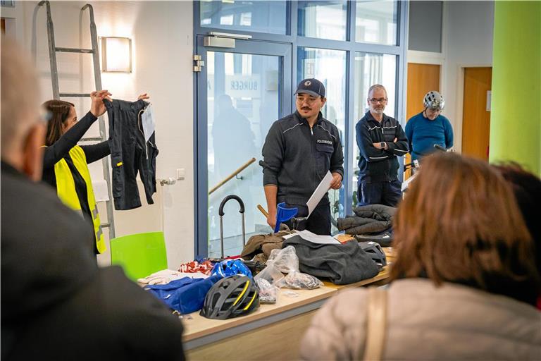Eine kurze schwarze Hose mit DHL-Aufnäher findet bei der Versteigerung keinen Abnehmer. Şebnem Demirok vom Backnanger Bürgeramt präsentiert nacheinander die verschiedenen Gegenstände, Daniel Fritz (Mitte) tritt als Auktionator auf.Foto: Alexander Becher