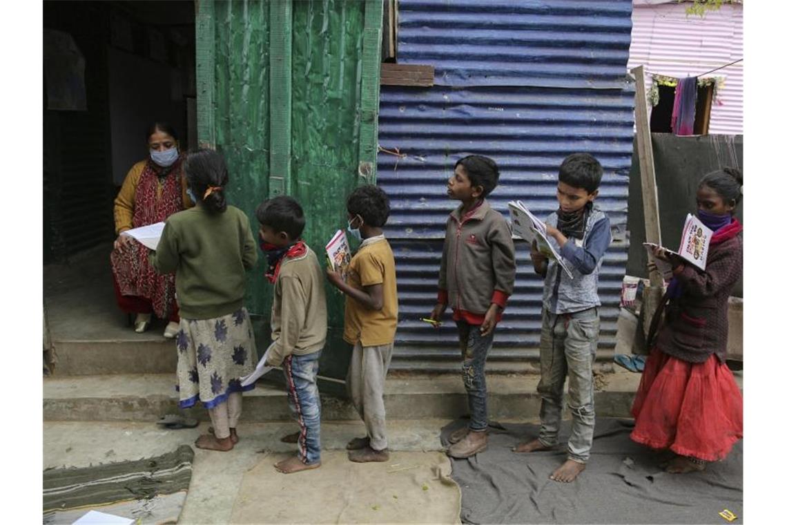 Eine Lehrerin in einem Armutsviertel am Rande der indischen Stadt Jammu korrigiert Schulhefte. Foto: Channi Anand/AP/dpa