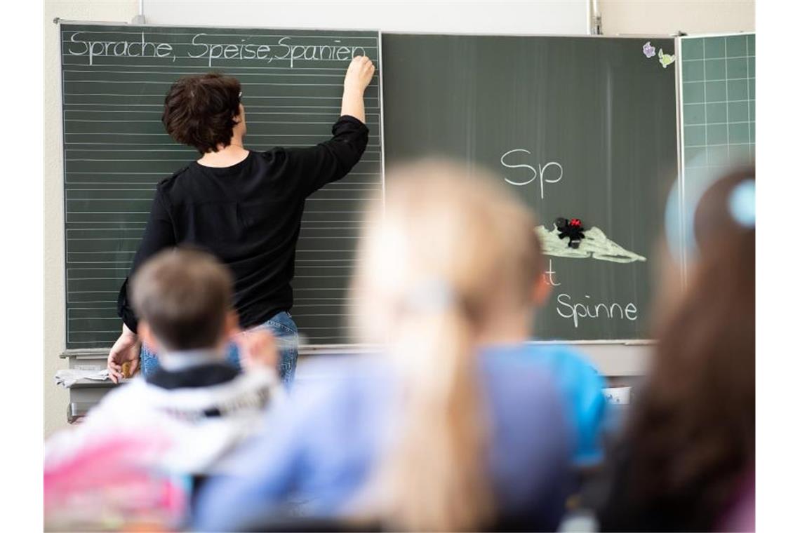 Eine Lehrerin schreibt in einer Schule an die Tafel. Foto: Sebastian Gollnow/dpa/Symbolbild