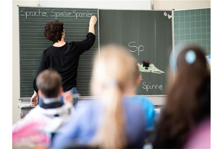 Eine Lehrerin schreibt in einer Schule an die Tafel. Foto: Sebastian Gollnow/dpa/Symbolbild