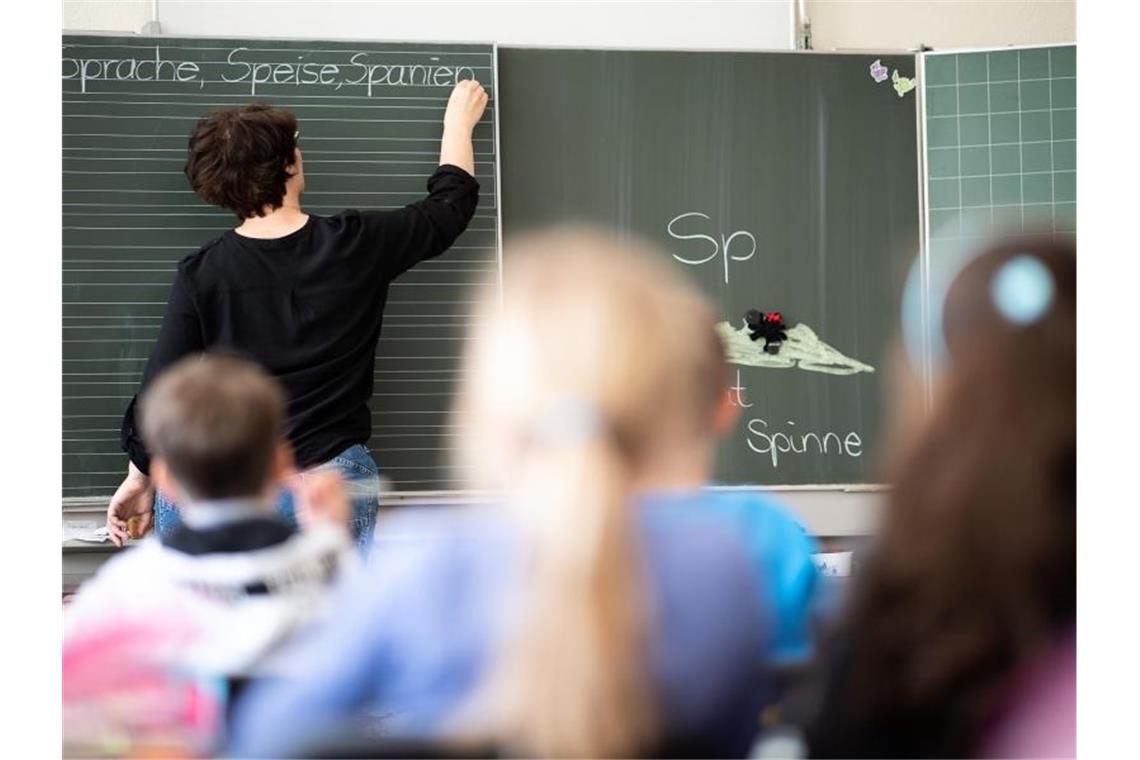 Schulen und Kitas öffnen trotz Sorge wegen Omikron-Zahlen Eine Lehrerin schreibt in einer Schule an die Tafel. Foto: Sebastian Gollnow/dpa/Symbolbild