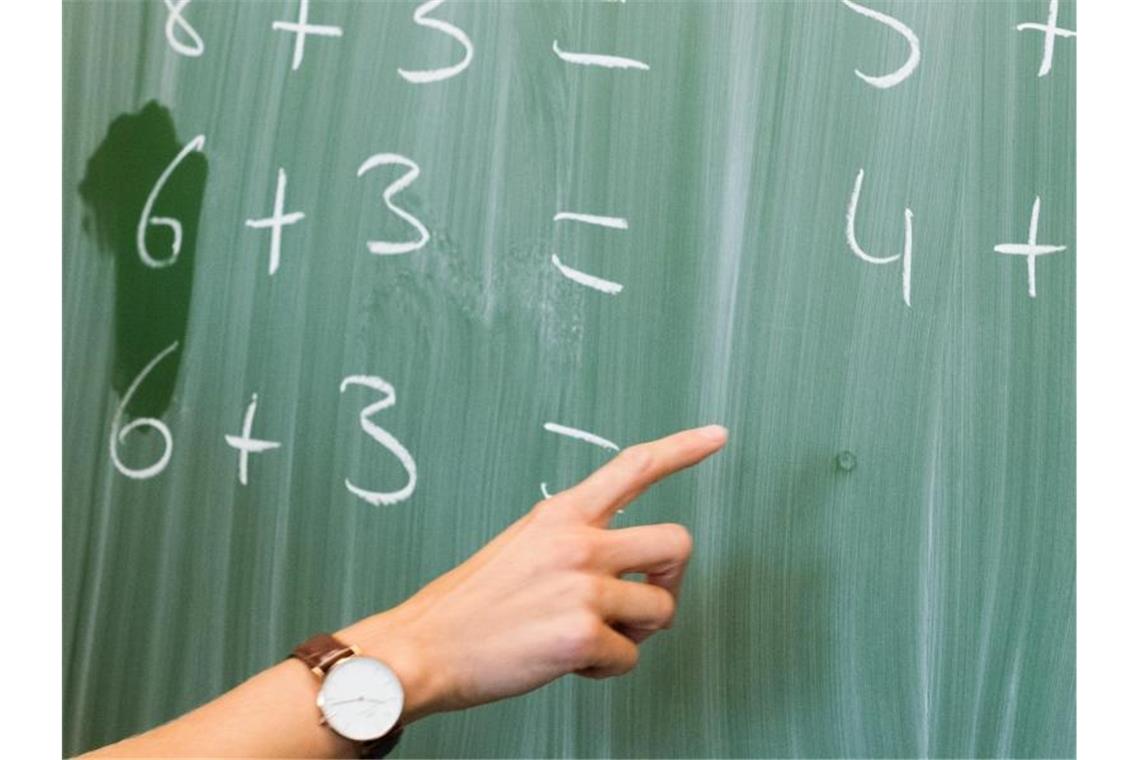 Eine Lehrerin schreibt in einer Schule Rechenaufgaben an eine Tafel. Foto: Julian Stratenschulte/dpa