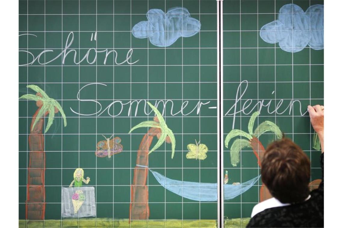 Ferienstart in sechs Bundesländern: Kaum Stau im Südwesten Eine Lehrerin schreibt „Schöne Sommerferien“ an eine Tafel in einer Grundschule. Foto: Ina Fassbender/dpa/Symbolbild