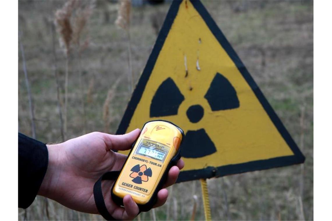 Eine Mann hält in der Nähe des Roten Waldes in der Sperrzone von Tschernobyl einen Geigerzähler in der Hand. Foto: ---/Ukrinform/dpa/Archivbild