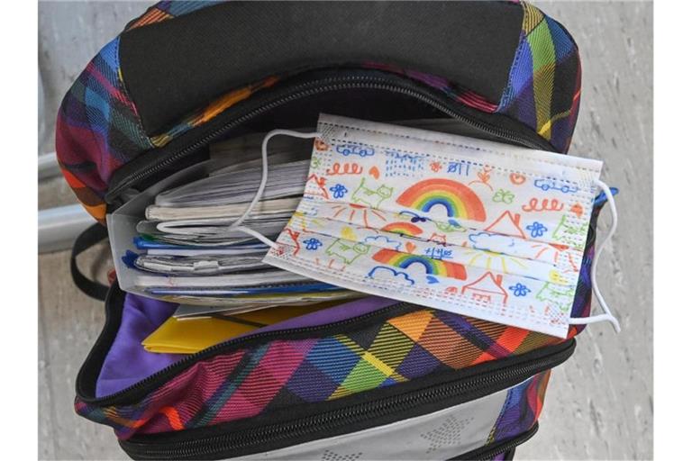 Eine Maske liegt auf dem Rucksack eines Grundschülers. Immer mehr Bundesländer kehren zum Regelunterricht zurück. Foto: Patrick Pleul/dpa-Zentralbild/ZB