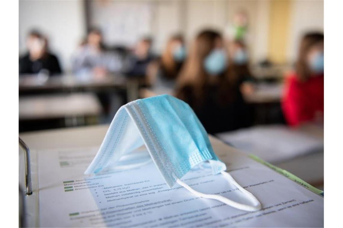 Grüner will weiterführende Schulen als nächstes öffnen Eine Maske liegt im Unterricht auf Unterlagen. Foto: Matthias Balk/dpa/Symbolbild