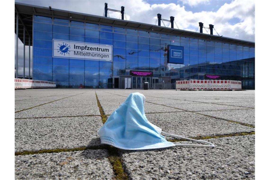 Eine Maske liegt vor dem Impfzentrum in der Messe Erfurt. In den ostdeutschen Bundesländern sind weniger Menschen gegen Covid-19 geimpft als bundesweit. Foto: Martin Schutt/dpa-Zentralbild/dpa