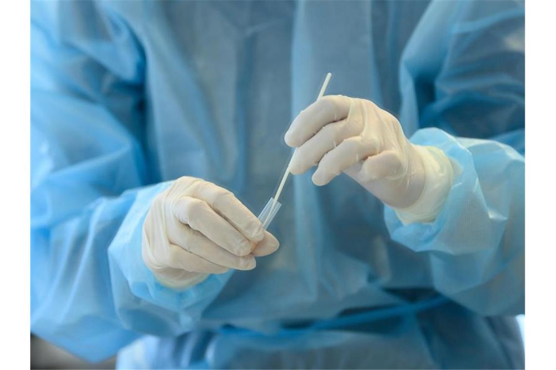 RKI registriert 13.565 Neuinfektionen - Inzidenz bei 82,7 Eine medizinische Mitarbeiterin entnimmt eine Nasenabstrichprobe für einen Coronatest. Foto: Robert Michael/dpa
