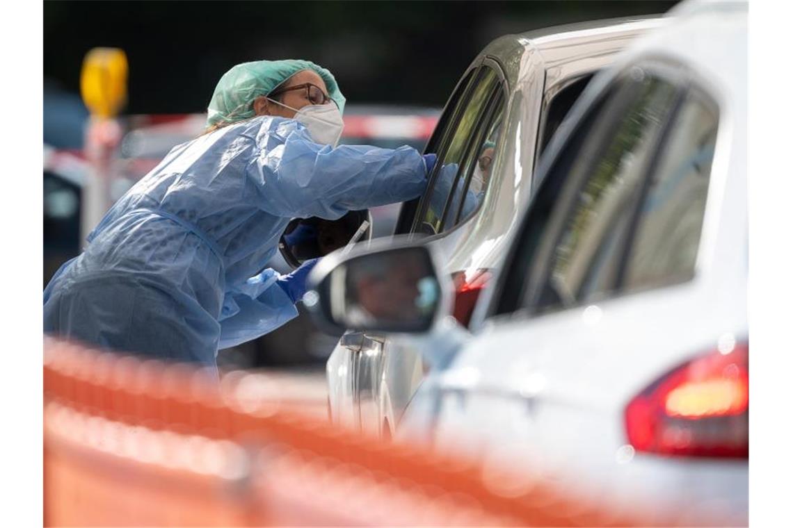 Eine medizinische Mitarbeiterin entnimmt einem Autofahrer einen Abstrich. Foto: Sebastian Gollnow/dpa