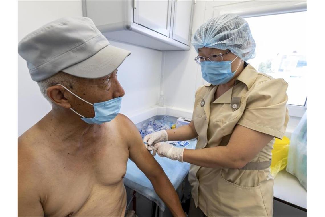 Eine medizinische Mitarbeiterin in Schutzkleidung injiziert einem Mann eine Dosis des Corona-Imfpstoffs Sputnik V in einem mobilen Impfzentrum auf der russischen Insel Sachalin. Foto: Sergey Krasnoukhov/AP/dpa