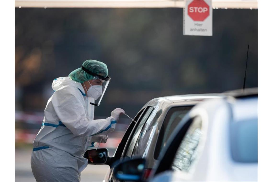 Eine medizinische Mitarbeiterin macht bei einem Autofahrer in Nürtingen einen Corona-Test. Foto: Tom Weller/dpa