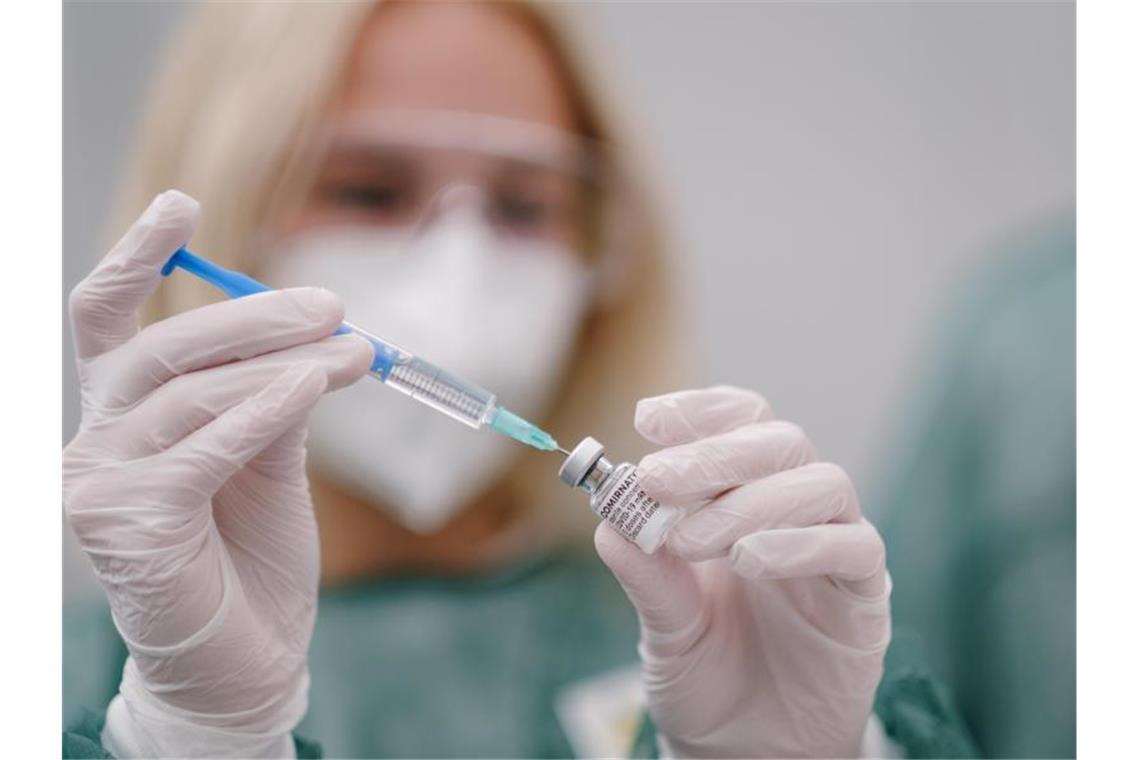 Eine medizinische Mitarbeiterin zieht in einem eine Spritze mit dem Covid-19 Impfstoff Comirnaty des Herstellers BionTech Pfizer auf. Foto: Ole Spata/dpa