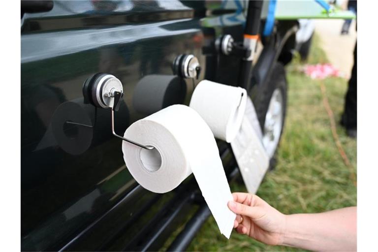 Eine Messebesucherin zieht an einer Toilettenpapierrolle, die mit einem Saugnapf an einem Auto befestigt ist. Foto: Felix Kästle