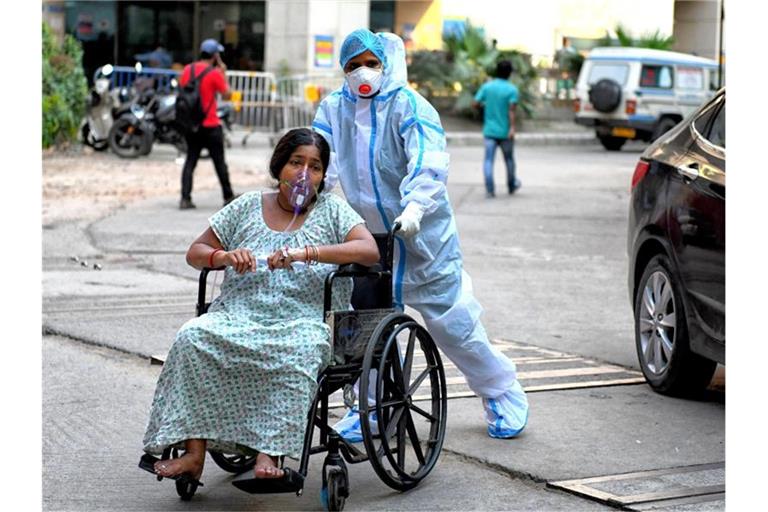 Eine mit dem Coronavirus infizierte Patientin sitzt im Rollstuhl und wird in das Kolkata Medical College Hospital eingeliefert. Foto: Avishek Das/SOPA Images via ZUMA Wire/dpa