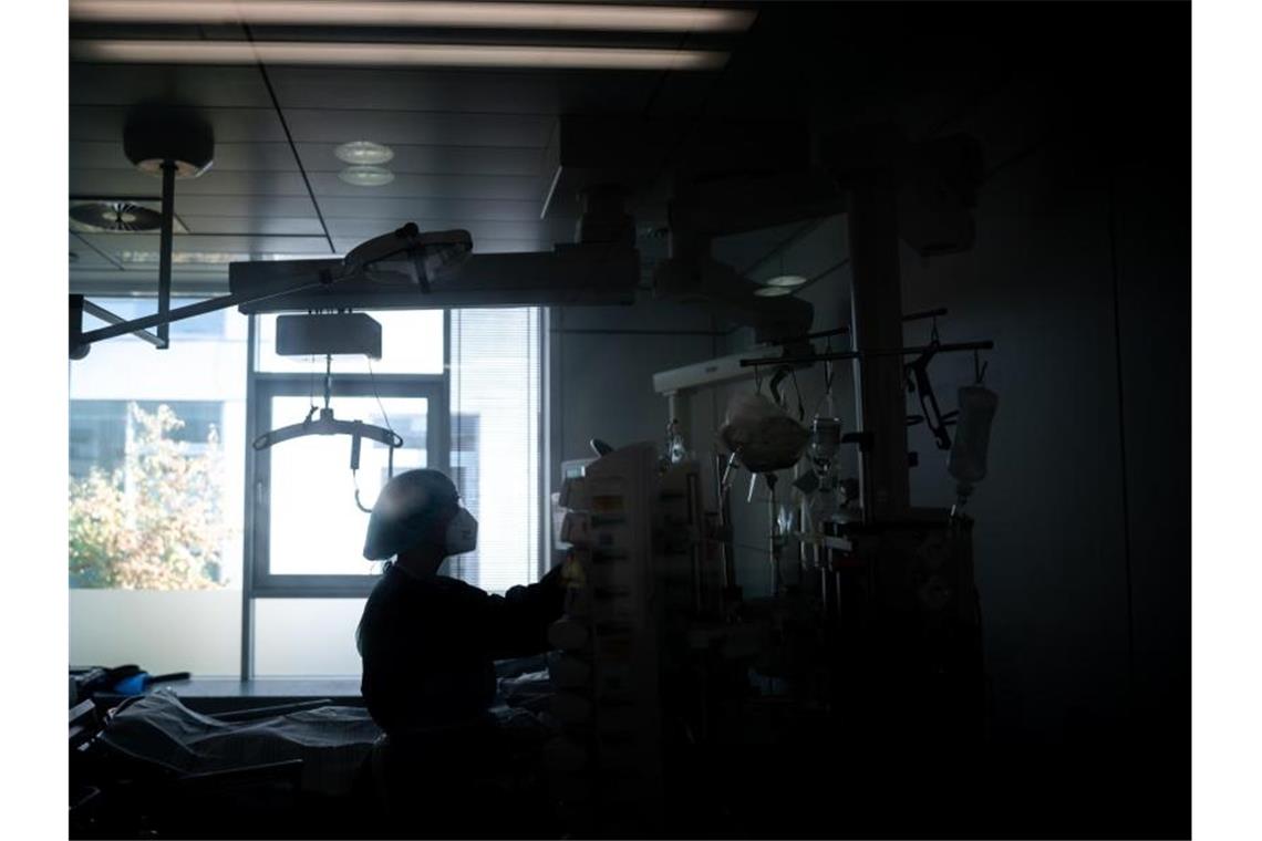 Eine Mitarbeiterin der Pflege steht in einem Zimmer einer Corona-Intensivstation. Foto: Fabian Strauch/dpa/Illustration