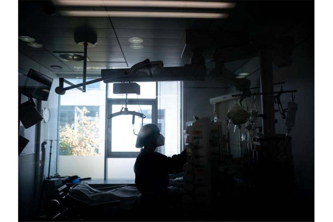 Hohe Zahl der Covid-19-Patienten auf Intensivstationen Eine Mitarbeiterin der Pflege steht in einem Zimmer einer Corona-Intensivstation. Foto: Fabian Strauch/dpa/Illustration