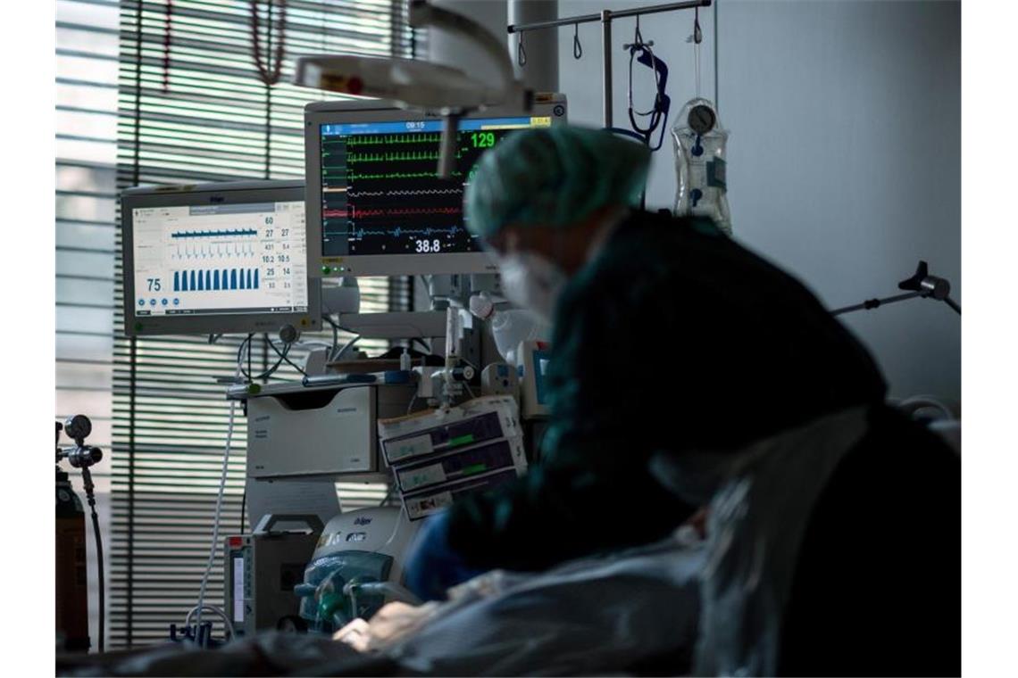 Anstieg der Corona-Fallzahlen kommt vermehrt in Kliniken an Eine Mitarbeiterin der Pflege versorgt einen Corona-Intensivpatienten. Foto: Fabian Strauch/dpa/Symbolbild