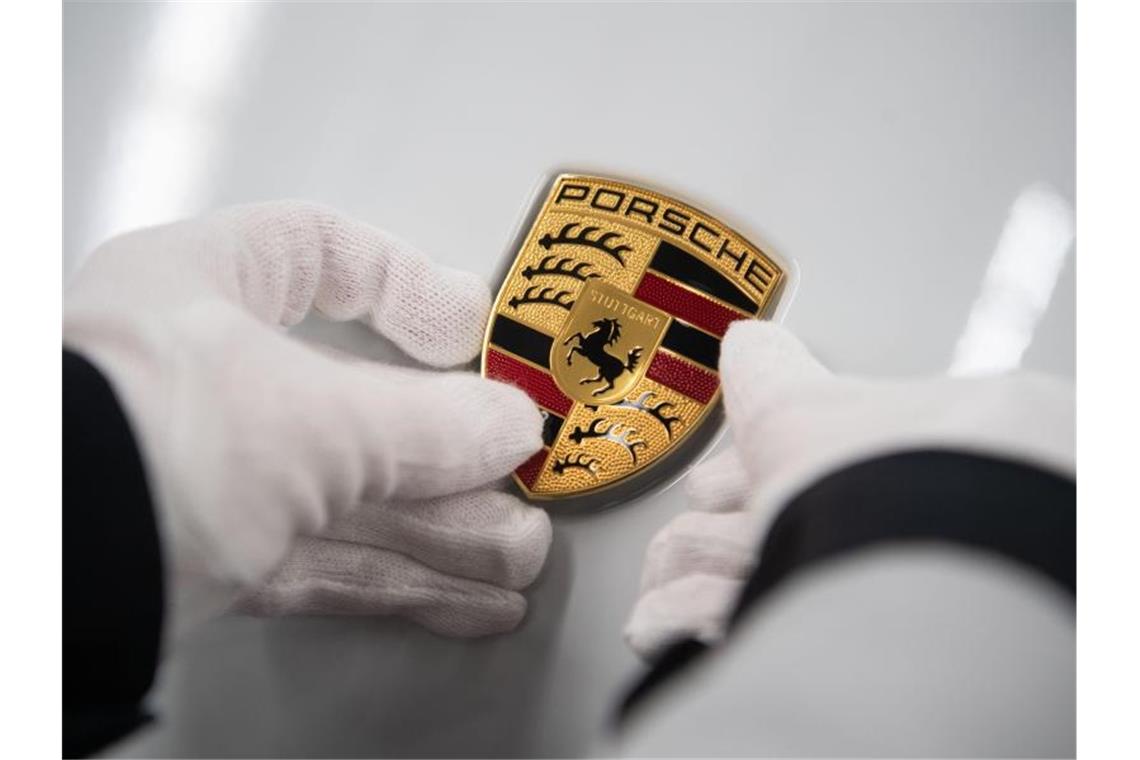 Eine Mitarbeiterin der Porsche AG hält in der Produktion ein Porsche-Emblem. Foto: Marijan Murat/dpa/Archivbild