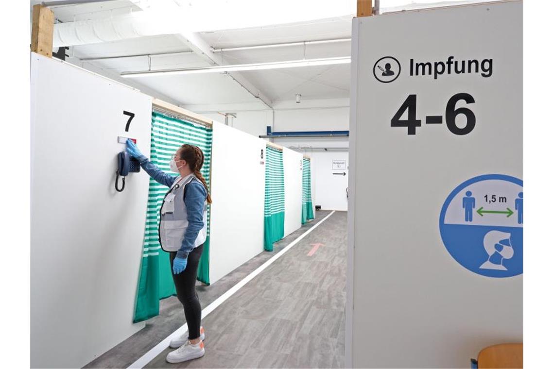 Erneuter Corona-Anstieg: Inzidenz jetzt bei 6,4 Eine Mitarbeiterin des Impfzentrums Attendorn richtet ein Schild vor einer Impfkabine im Impfzentrum. Foto: Rene Traut/dpa