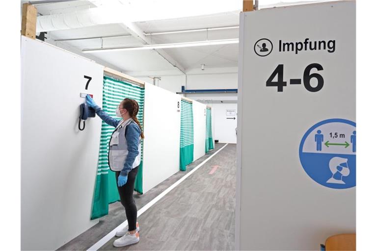 Eine Mitarbeiterin des Impfzentrums Attendorn richtet ein Schild vor einer Impfkabine im Impfzentrum. Foto: Rene Traut/dpa