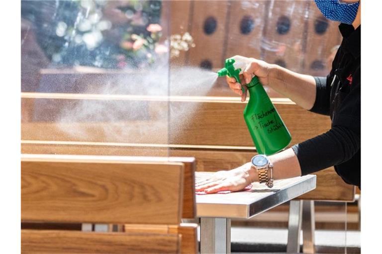 Eine Mitarbeiterin eines Restaurants reinigt einen Tisch. Foto: Robert Michael/dpa-Zentralbild/dpa/Symbolbild