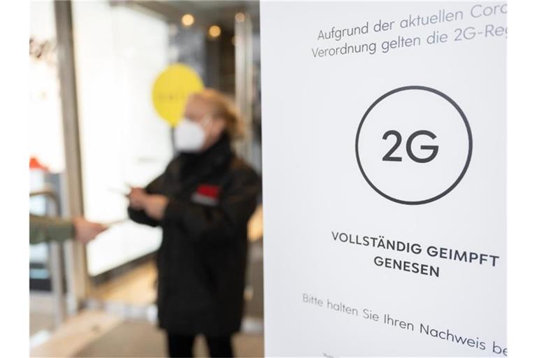 Eine Mitarbeiterin eines Stuttgarter Kaufhauses kontrolliert den Impfnachweis einer Kundin. Foto: Bernd Weißbrod/dpa