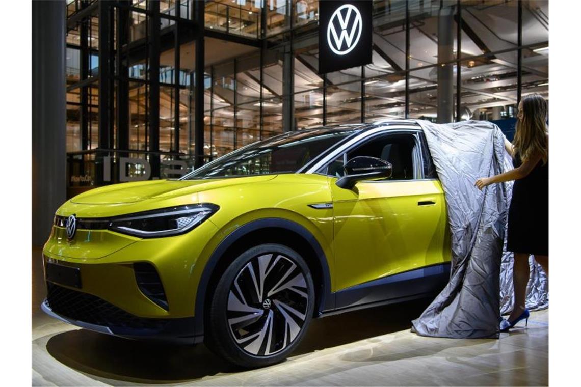 Eine Mitarbeiterin enthüllt während der Vorstellung in der Gläsernen Manufaktur einen ID.4 von Volkswagen, dem ersten Elektro-SUV der Marke. (Archivbild). Foto: Robert Michael/dpa-Zentralbild/dpa