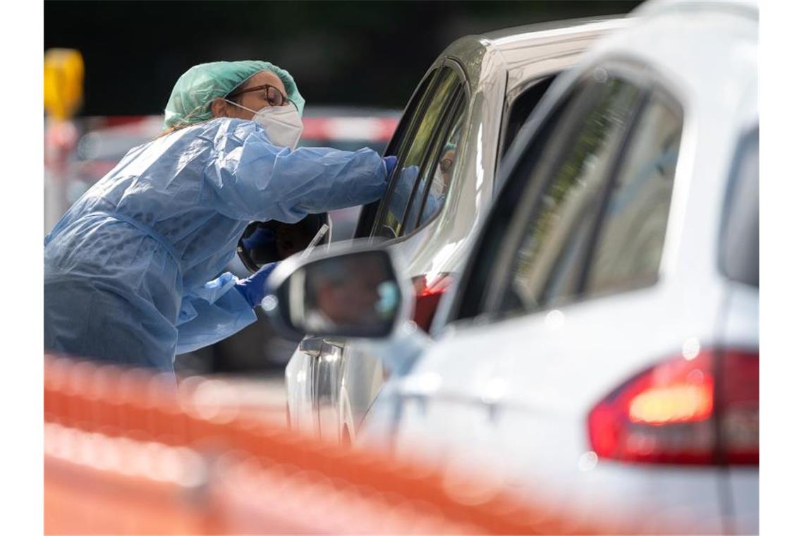 Erneut mehr als 4000 Corona-Neuinfektionen - Was heißt das? Eine Mitarbeiterin im Landkreis Esslingen macht im Corona-Abstrich-Zentrum bei einem Autofahrer einen Abstrich. Foto: Sebastian Gollnow/dpa