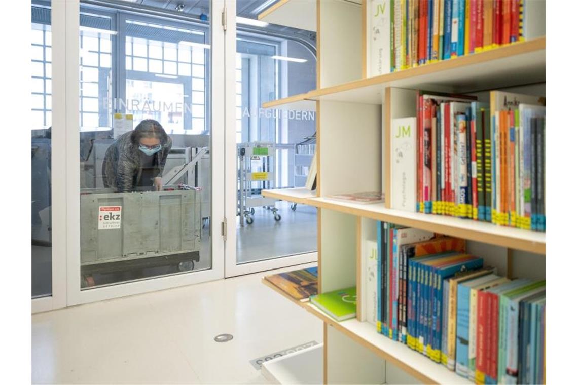 Eine Mitarbeiterin legt in einer Bibliothek ein Buch in die Quarantänebox. Foto: Sebastian Gollnow/dpa
