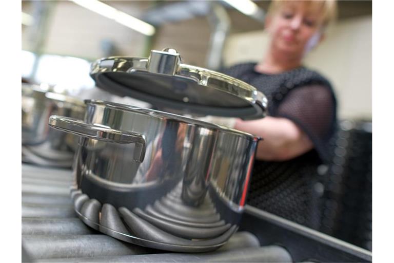 Eine Mitarbeiterin setzt im Stammwerk des Küchengeräteherstellers Württembergische Metallwarenfabrik AG (WMF) in Geislingen einen Deckel auf einen fertiggestellten Topf. Foto: Uwe Anspach