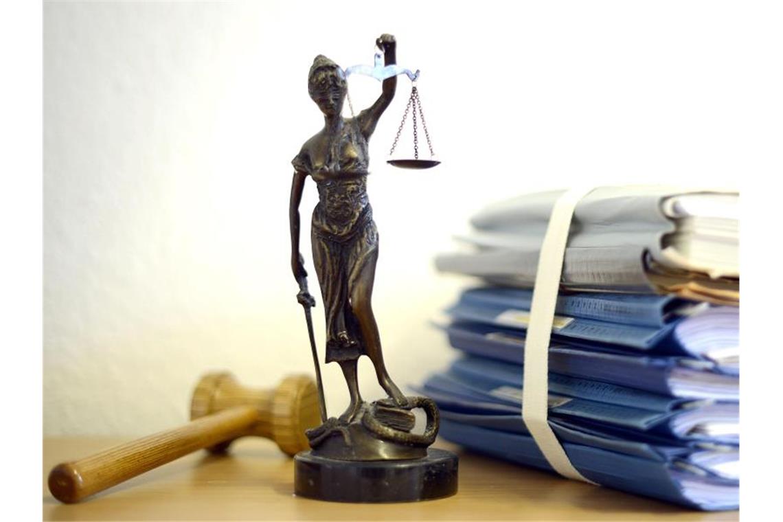 Eine modellhafte Nachbildung der Justitia steht neben Akten und einem Richterhammer auf einem Tisch. Foto: Volker Hartmann/dpa/Archivbild