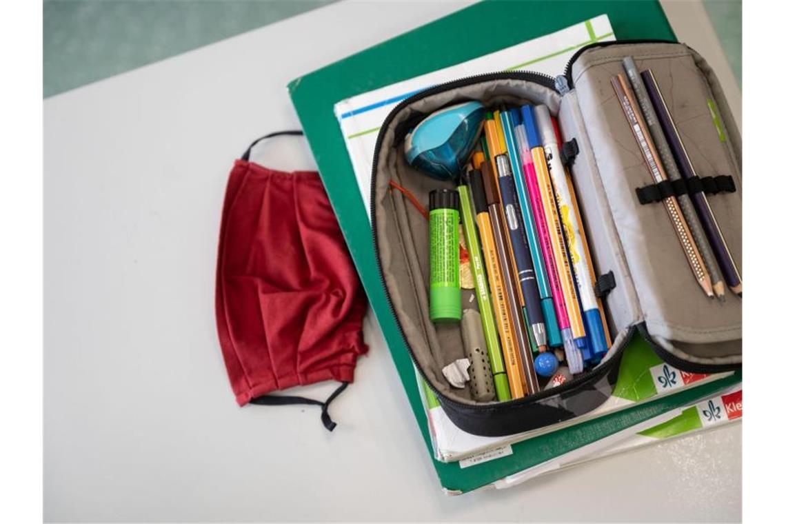 Stuttgart will Luftreiniger an ausgewählten Schulen testen Eine Mund-Nasen-Bedeckung liegt neben einem Mäppchen auf einem Tisch. Foto: Marijan Murat/dpa/Symbolbild