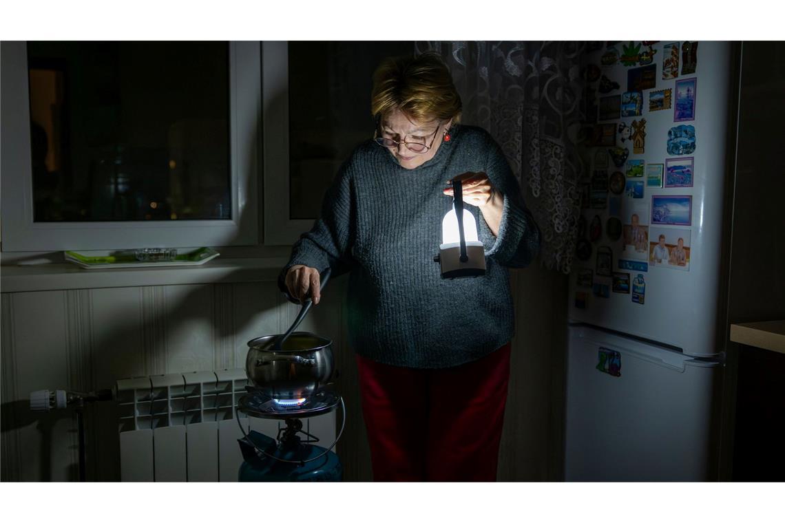 Eine Mutter kocht auf einem Gasbrenner nach einem Stromausfall in Kiew durch einen russischen Angriff.