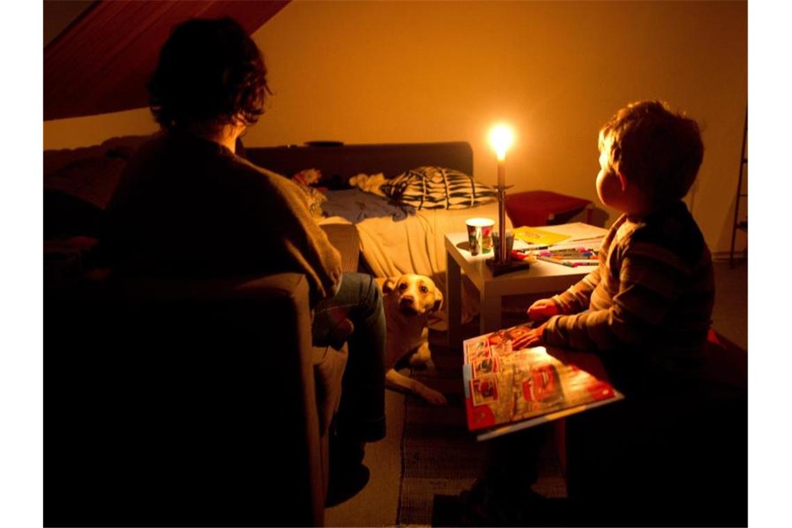 Eine Mutter sitzt mit ihrem Sohn in ihrer abgedunkelten Wohnung. Foto: Julian Stratenschulte/dpa