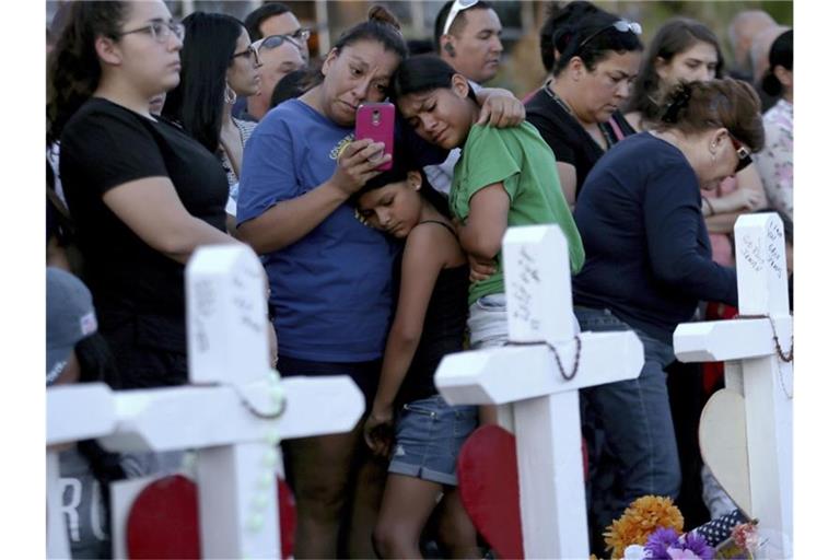 Eine Mutter umarmt ihre Töchter hinter Kreuzen, die zum Gedenken aufgestellt wurden. Foto: Mark Lambie/The El Paso Times/AP