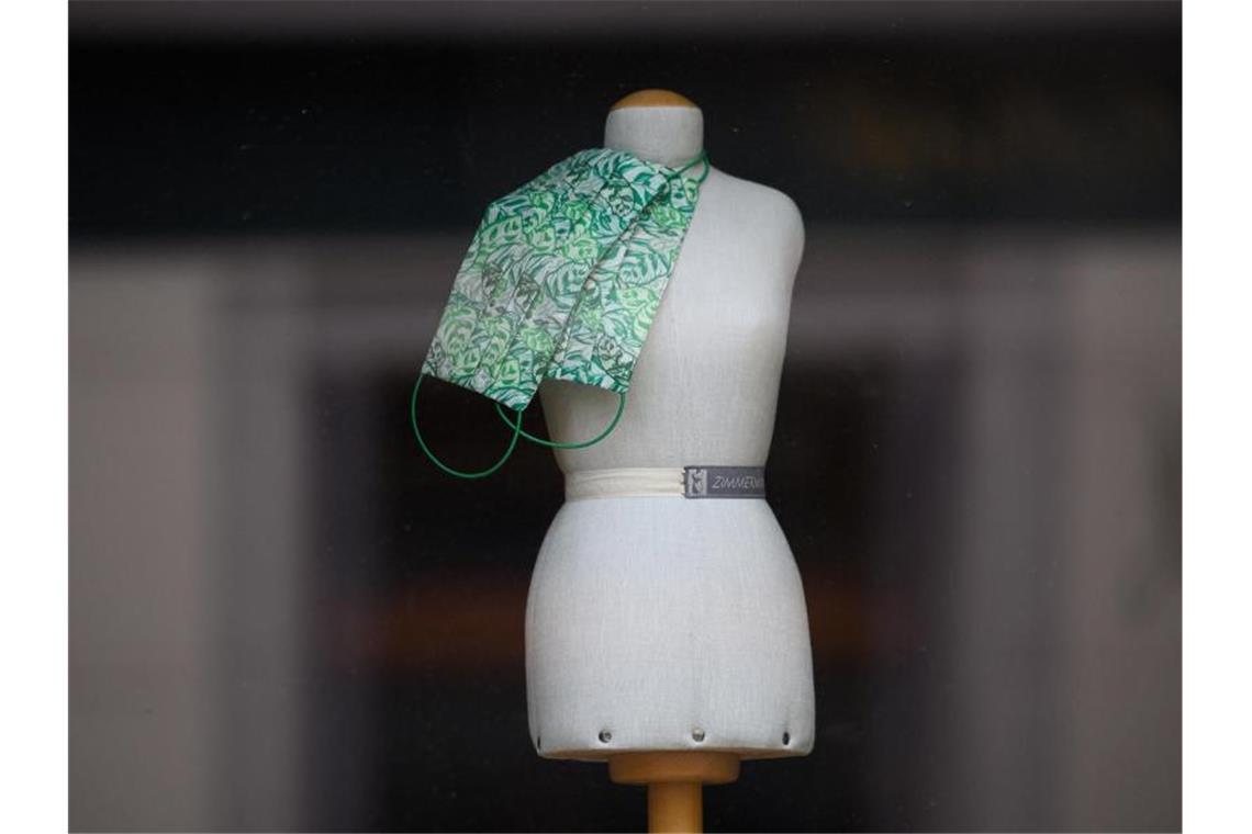 Handel warnt vor schärferem Lockdown Eine nur noch mit Mund-und Nasenschutzmasken bestückte Puppe im Schaufenster eines Modeladens. Foto: Robert Michael/dpa-Zentralbild/dpa