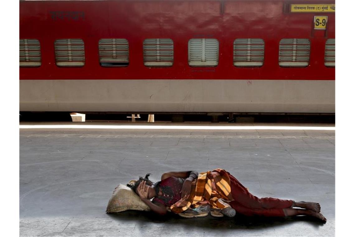 Eine obdachlose Frau schläft auf einem aufgrund der Corona-Pandemie leeren Bahnsteig in einem Vorort von Mumbai. Foto: Rafiq Maqbool/AP/dpa