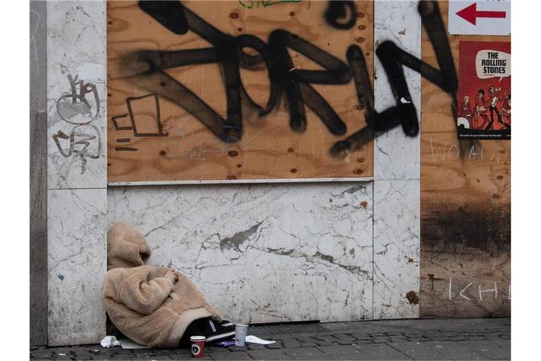 Eine obdachlose Frau schützt sich im Bahnhofsviertel von Frankfurt am Main mit einer Jacke gegen die Kälte. Foto: Boris Roessler/dpa