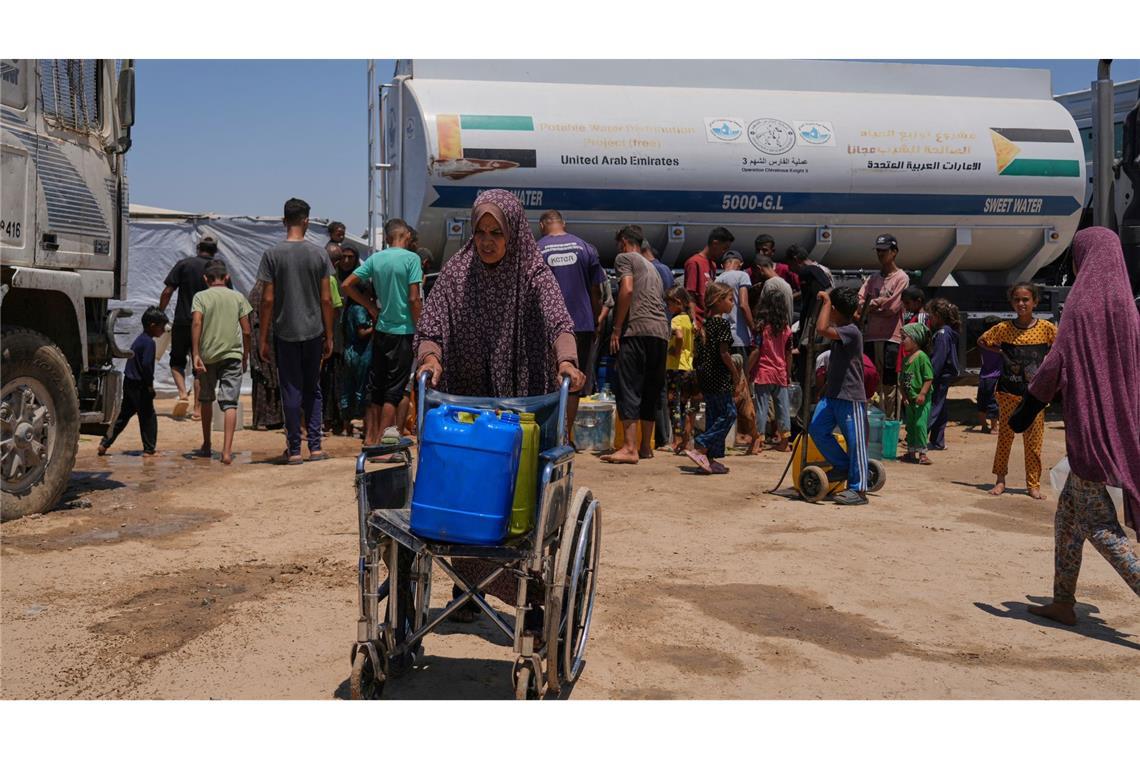 Eine palästinensische Frau schiebt einen Rollstuhl mit Plastikkanistern mit Wasser im Gazastreifen.