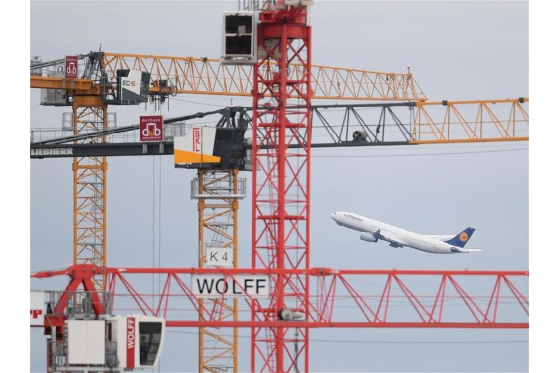 Flughafenbetreiber Fraport von Coronavirus schwer getroffen Eine Passagiermaschine der Lufthansa startet auf dem Frankfurter Flughafen hinter Baukränen. Foto: Arne Dedert/dpa/Archivbild