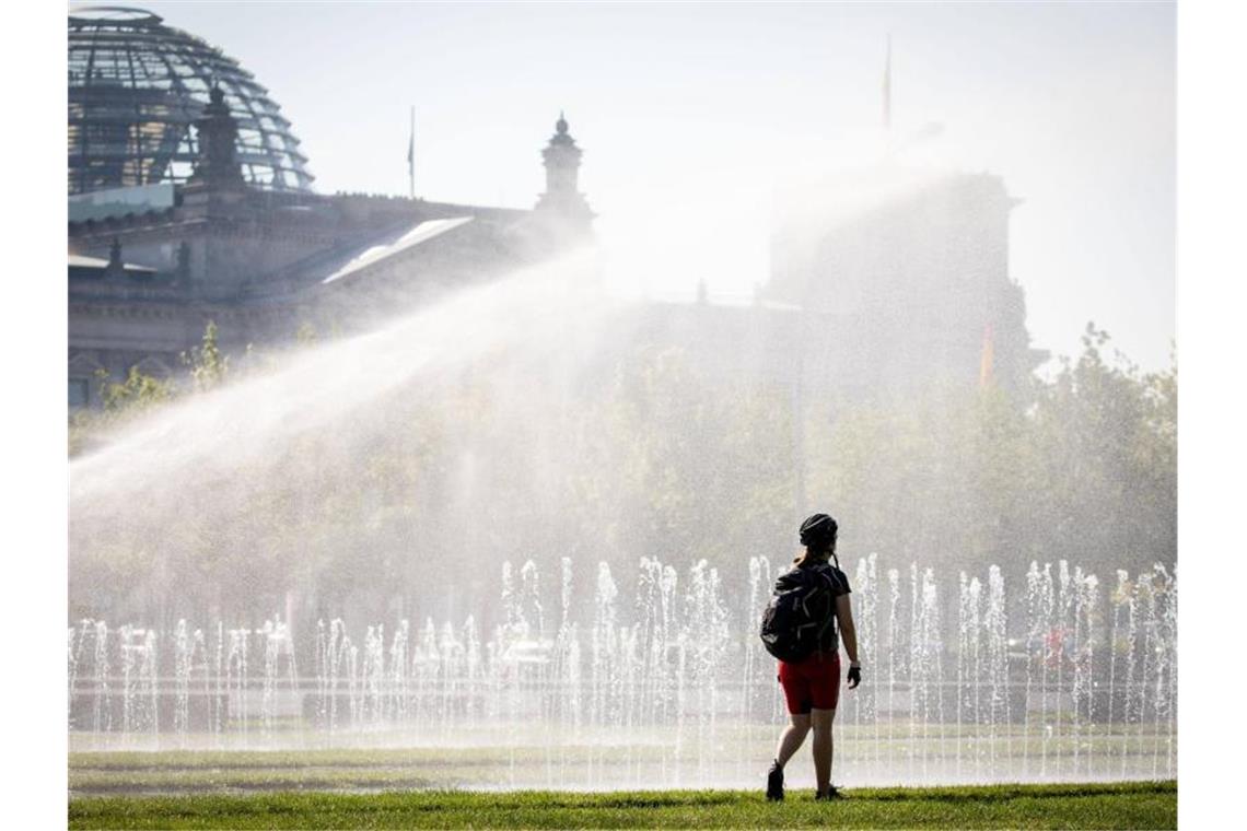 Eine Passantin erfrischt sich in einer Wasserfontäne vor dem Reichstag in Berlin. Nicht nur die Hauptstadt schwitzt. Foto: Kay Nietfeld