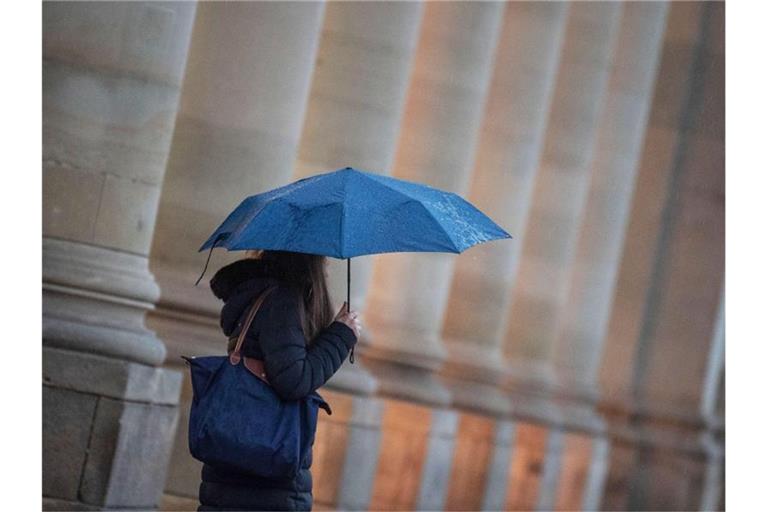 Eine Passantin geht bei Regen durch die Stadt. Foto: Marijan Murat/dpa/Symbolbild