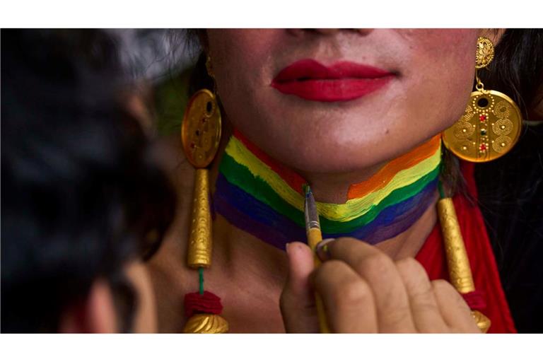 Eine Person bekommt den Hals in Regenbogenfarben für die Pride Parade in Kathmandu, Nepal bemalt.