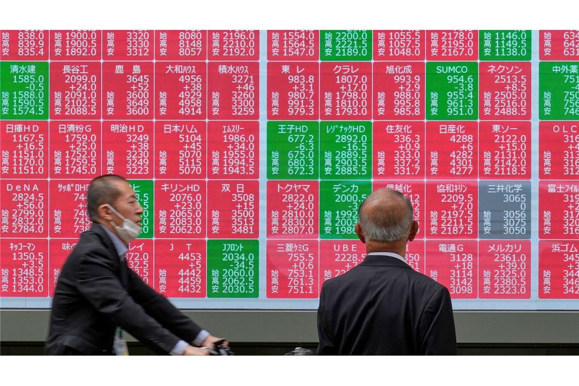 Eine Person blickt auf eine elektronische Börsentafel, die den japanischen Nikkei-Index anzeigt, in einer Wertpapierfirma in Tokio.